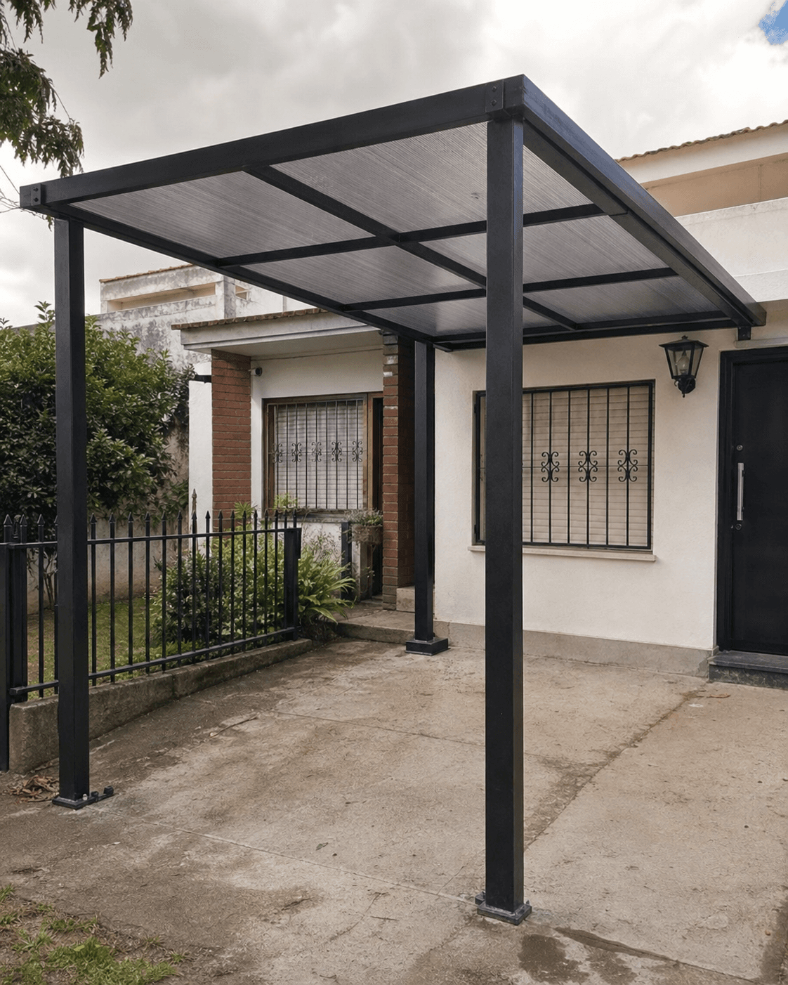 Estructura metálica negra con techo de policarbonato instalada en una cochera