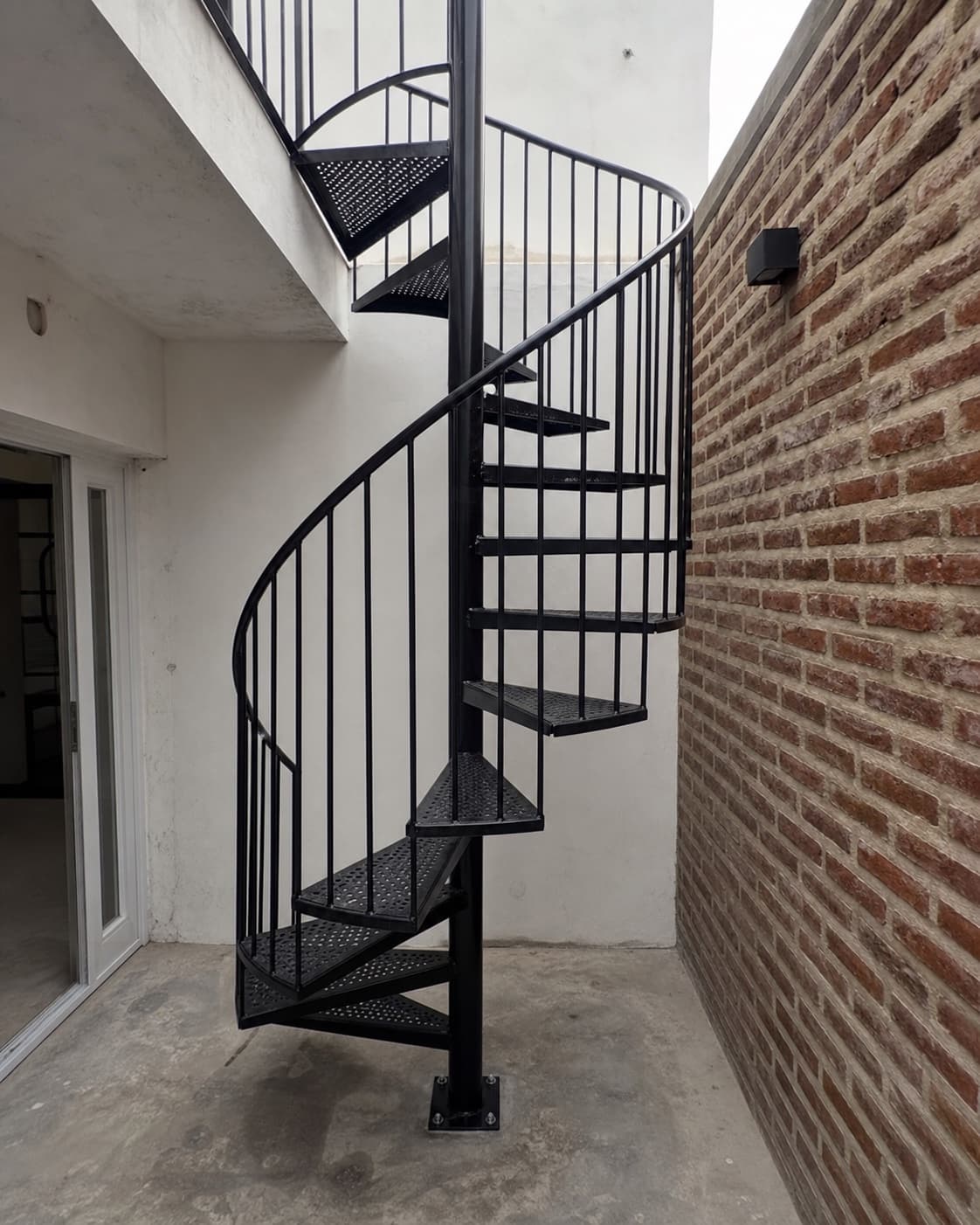 Escalera caracol de hierro negro instalada en patio interior