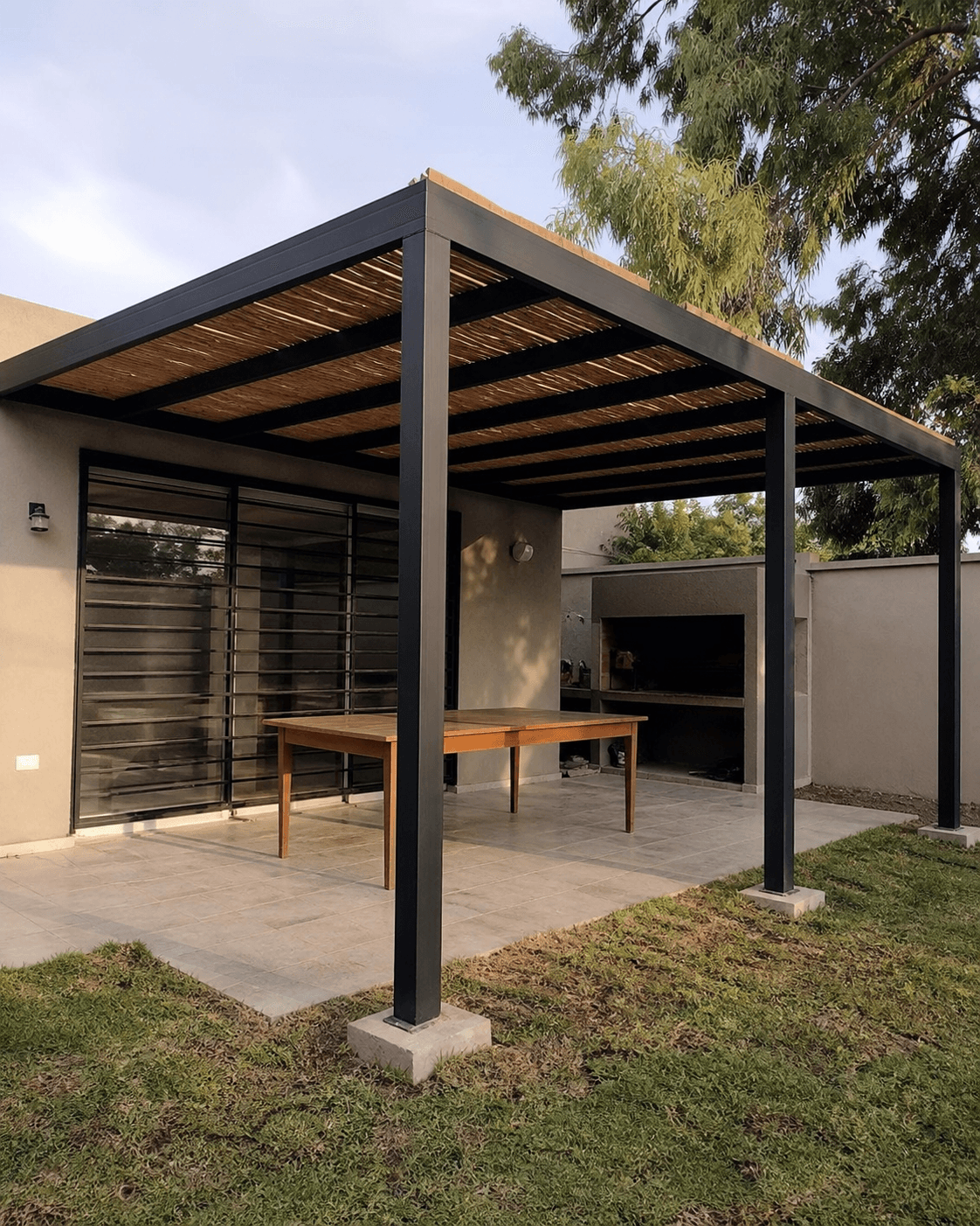 Pérgola de estructura metálica negra y listones de madera instalada en un patio