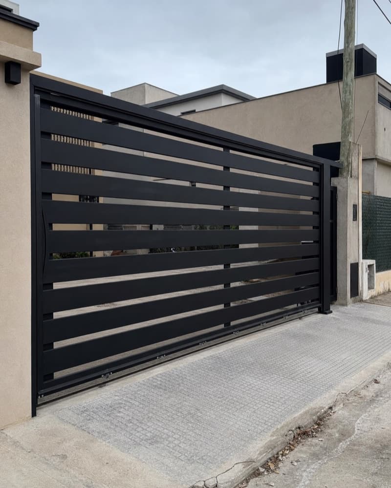 Portón corredizo de acero negro con paños horizontales fabricado a medida en Zona Sur del GBA